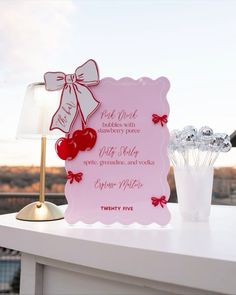 a pink sign sitting on top of a white table next to a vase filled with candy