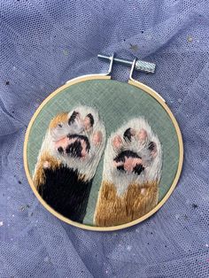 a close up of a small embroidery hoop with a cat's paw on it