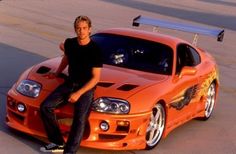 a man sitting on top of an orange sports car