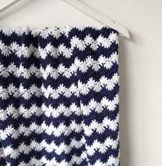 a blue and white crocheted blanket hanging on a wall next to a hanger