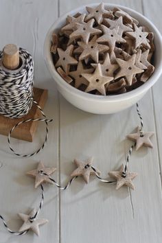 a bowl filled with star shaped cookies next to spools of twine on a white table