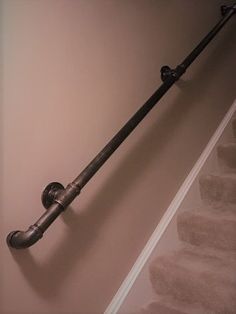 an iron pipe is attached to the side of a stair case in a home with beige walls