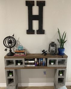 a book shelf with some books on top of it next to a wall mounted letter h