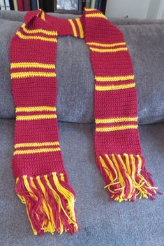 a red and yellow striped scarf sitting on top of a couch next to a book shelf