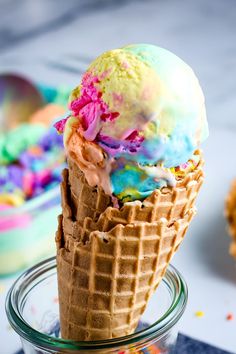 two scoops of ice cream with sprinkles in a glass container on a table