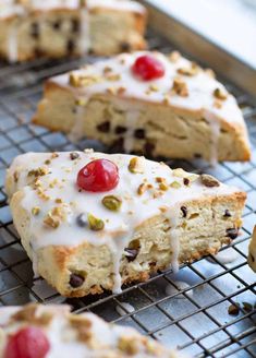 there is a piece of cake with white frosting and cherries on it, sitting on a cooling rack