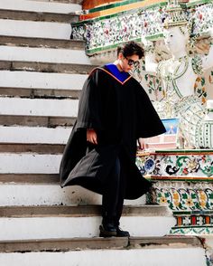 a man in a graduation gown walking up some steps