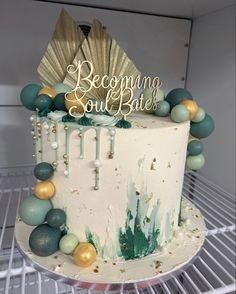 a decorated cake sitting on top of a metal rack next to a white refrigerator freezer