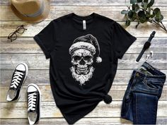 Gothiccore Skull Wearing Santa Hat Shirt, Cool Christmas Graphic Tee, Skeleton Holiday Party Shirt, Gothic Xmas T-Shirt, Metal Lover Apparel, Unisex Description Embrace your Gothic style this holiday season with this edgy skull wearing a Santa hat shirt 🎅💀. Perfect for Christmas parties, music festivals, or just showing off your love for the darker side of the holidays, this unique tee combines festive cheer with a Gothic twist. High-quality fabric for long-lasting comfort and durability Bold, Black Christmas Streetwear T-shirt, Black T-shirt For Christmas Streetwear, Black Festive Streetwear T-shirt, Black Winter Holiday T-shirt, Christmas Streetwear Cotton T-shirt, Christmas Cotton T-shirt For Streetwear, Cotton Christmas T-shirt For Streetwear, Casual Halloween T-shirt For Gift, Casual Halloween Holiday Tops