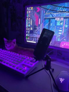 a cat sitting in front of a computer keyboard and mouse on a desk with purple lighting