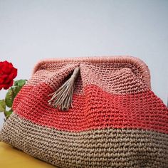 a pink and brown purse sitting on top of a table next to a red rose