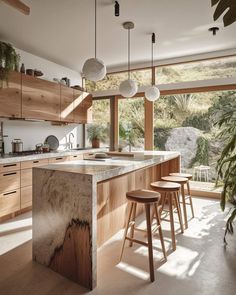 a kitchen with wooden cabinets and stools next to an open window overlooking the mountains