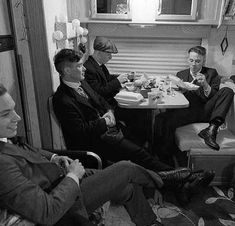 four men sitting around a table eating food