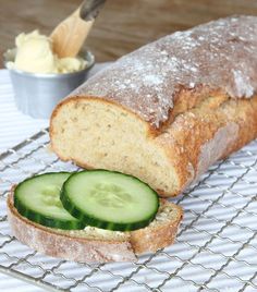 a loaf of bread sitting on top of a cooling rack with cucumber slices