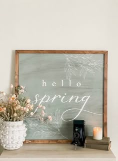 a sign that says hello spring next to a vase with flowers