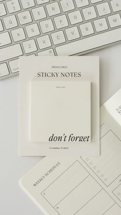 sticky notes sitting on top of a desk next to a keyboard and paper with the word don't forget written on it