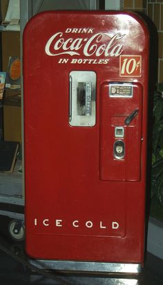 an old coca - cola machine sitting on top of a table