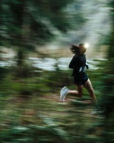 a blurry photo of a person running through the woods with trees in the background