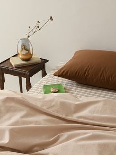 a small table with a vase on top of it next to a bed