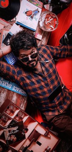 a man laying on top of a red couch next to a table filled with records