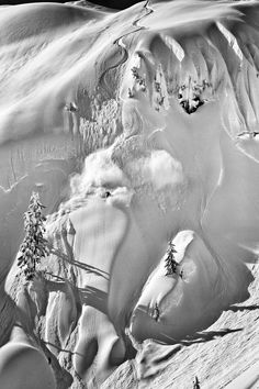 an aerial view of snow covered mountains and trees