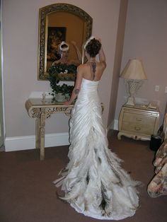 a woman in a wedding dress looking at herself in the mirror