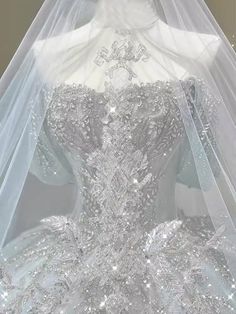 a white wedding dress with silver sequins on the bottom and veil over it