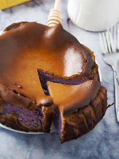 a chocolate cake on a white plate with a bite taken out of it and two forks next to it