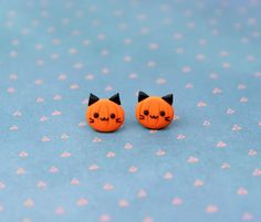 two small pumpkins with black ears are sitting on a blue surface