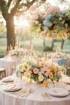 a table set with flowers and candles for an outdoor wedding reception in the sunbeams