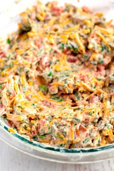 a casserole dish with cheese and other toppings in a glass bowl on a white table