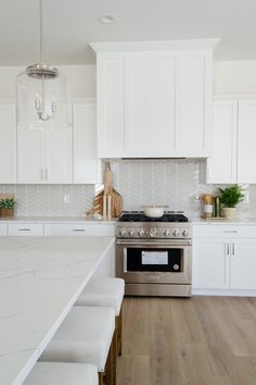 a kitchen with white cabinets and stainless steel stove top oven in the middle of it