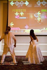 two people in costume are playing video games on a large projector screen behind them