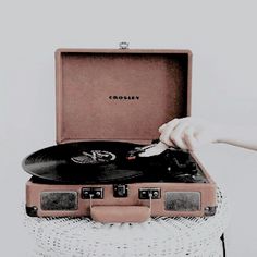 an old record player sitting on top of a white wicker basket filled with vinyl records