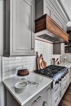 a kitchen with gray cabinets and white marble counter tops is pictured in this image, there are wooden utensils on the stovetop