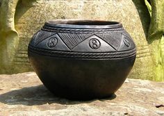 a black vase sitting on top of a rock