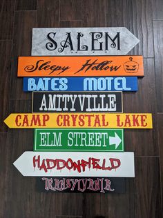 several different colored street signs mounted to the side of a wooden wall in front of a wood floor