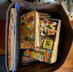 an open book is sitting in a brown box on the floor next to other books