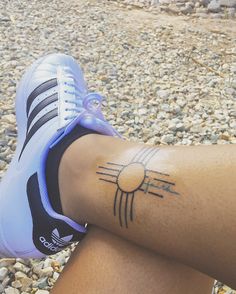 a woman's legs with a tattoo on the side of her leg and an adidas shoe