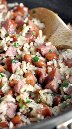 rice and beans are mixed together in a skillet with a wooden spoon on the side