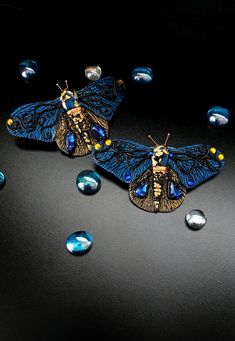 Introducing our Gothic Blue and Gold Butterfly Hairclips - a charming accessory that melds dark elegance with a touch of regal charm. Handcrafted for those who revel in the mystique of gothic aesthetics, these hairclips features an exquisite butterfly design in rich shades of deep blue and opulent gold. The intricate detailing of the butterfly's wings, adorned with subtle gothic motifs, adds an air of enchantment to your hairstyle. The juxtaposition of dark and royal hues creates a captivating accessory that effortlessly transitions from everyday wear to special occasions. Made with meticulous craftsmanship, the hairclip is both sturdy and lightweight, ensuring a comfortable and secure hold. Elevate your look with a hint of otherworldly sophistication as the Gothic Blue and Gold Butterfly Handmade Blue Brooches For Party, Unique Blue Brooch For Party, Unique Blue Brooches For Party, Elegant Blue Butterfly Brooches, Gold Butterfly Brooch For Party, Blue And Gold Butterfly, Gothic Motifs, Butterfly Handmade, Wedding Barrettes