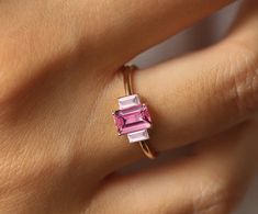 a woman's hand with a pink tourmaline ring on it