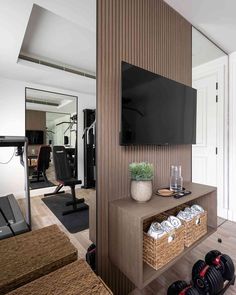 a living room with a flat screen tv on the wall and gym equipment in the background