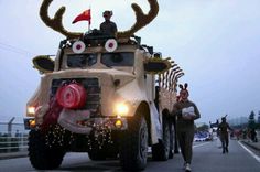 people are walking down the street in front of a vehicle with antlers on it