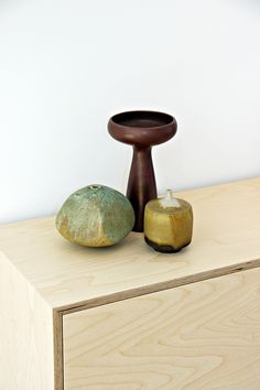 two pieces of fruit sitting on top of a wooden dresser next to a candle holder