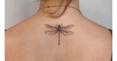 the back of a woman's neck with a dragonfly tattoo on it