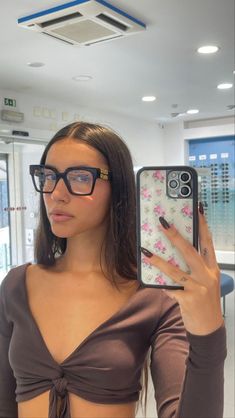 a woman wearing glasses holding up a cell phone in front of her eyeglasses