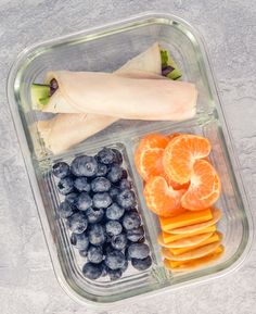 a plastic container filled with fruits and veggies on top of a gray surface