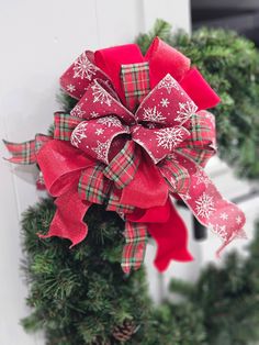 a red and green christmas wreath with snowflakes hanging on the side of a door