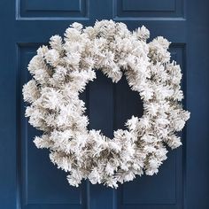 a white wreath hanging on a blue door